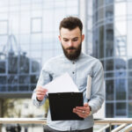 portrait-young-businessman-checking-document-front-office-building